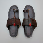 Pair of black sandals with brown straps on a textured surface