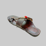 Brown sandal with decorative thong on a textured beige surface