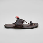 Brown sandal with a decorative strap on a light-colored floor