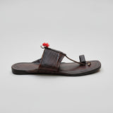 Brown sandal with a decorative strap on a light-colored floor