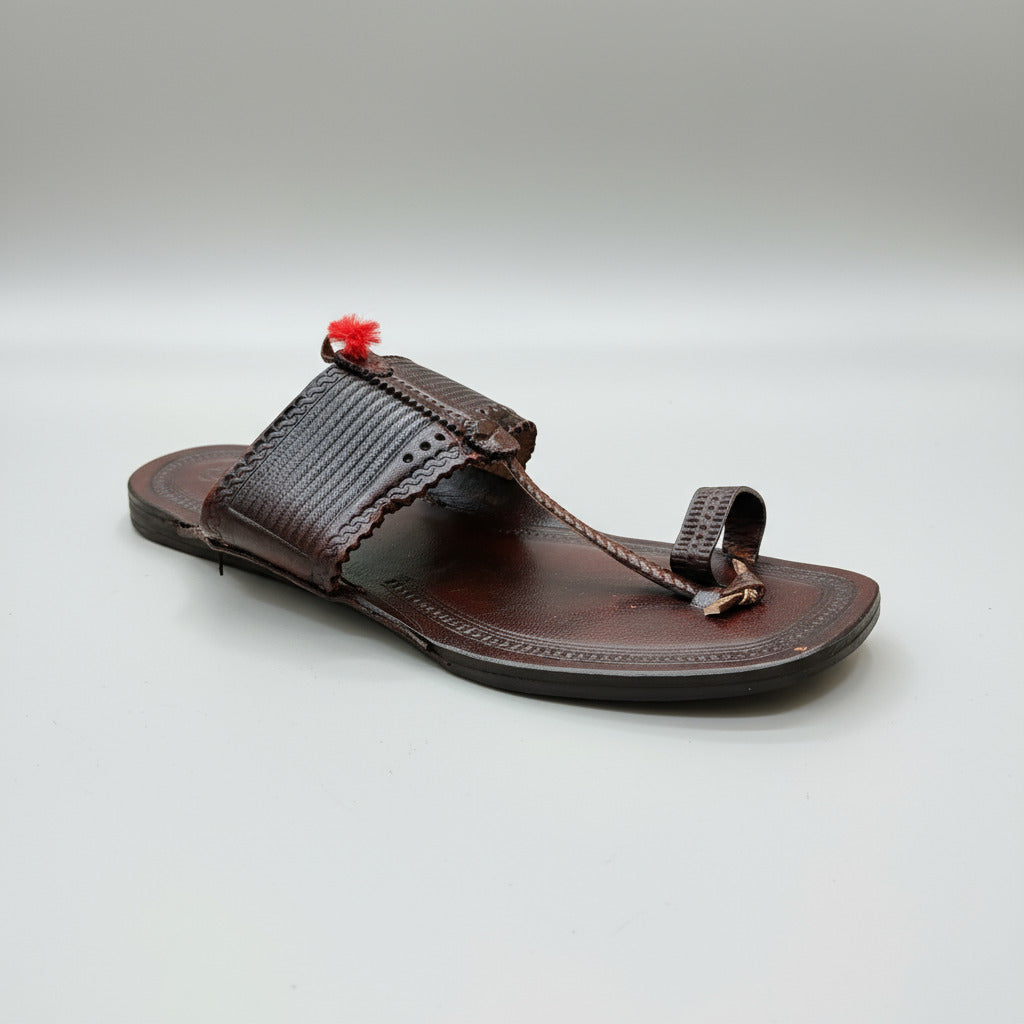 Brown sandal with decorative strap on a light marble surface