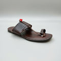 Brown sandal with decorative strap on a light marble surface