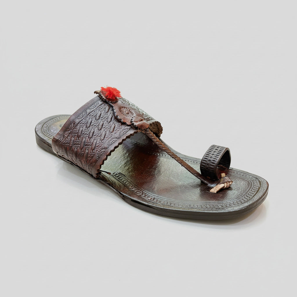 Brown sandal with decorative elements on a textured beige surface