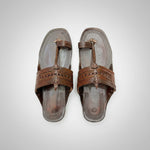 Pair of brown sandals with decorative straps on a beige background