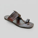 Brown sandal with decorative straps on a light-colored floor