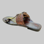 Brown sandal with decorative straps on a light beige surface