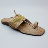 Brown sandal with decorative elements on a light gray surface