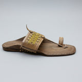 Brown sandal with decorative straps on a light-colored floor