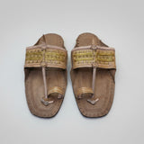 Pair of brown sandals with gold straps on a textured white surface