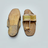 Pair of traditional sandals with decorative straps on a textured white surface