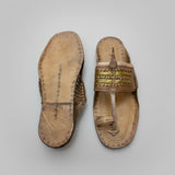 Pair of worn sandals on a textured white surface
