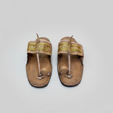 Pair of traditional sandals with decorative straps on a light textured surface