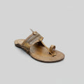 Brown sandal with decorative straps on a light gray surface