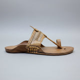 Brown sandal with decorative straps on a light gray surface