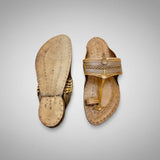Pair of tan sandals with decorative straps on a light gray background