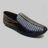 Black perforated leather shoe on a textured surface