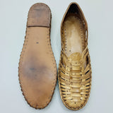 Pair of leather kolhapuri clogs on a textured surface