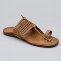A single brown leather thong sandal with woven detailing and a toe loop, resting on a polished light gray marble floor.