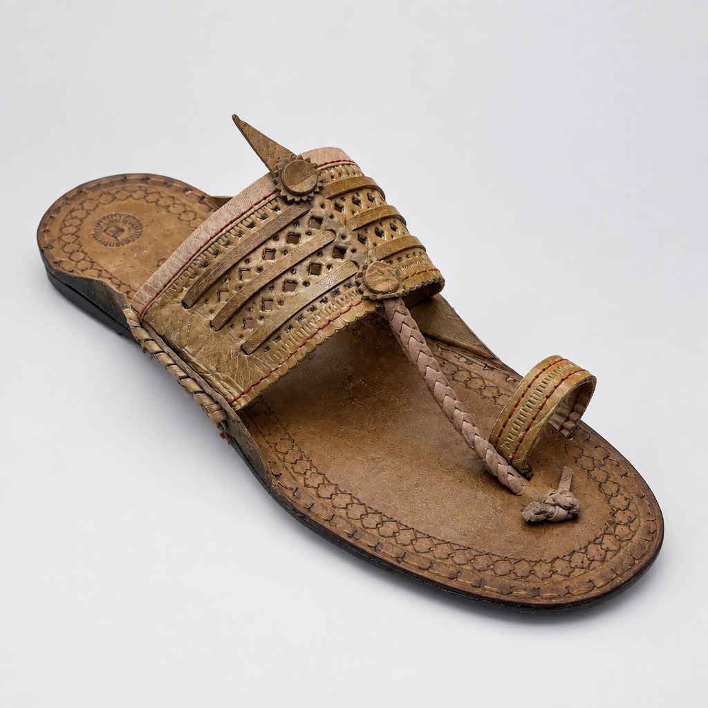 A single brown leather thong sandal with woven detailing and a pointed toe, resting on a polished beige marble floor.