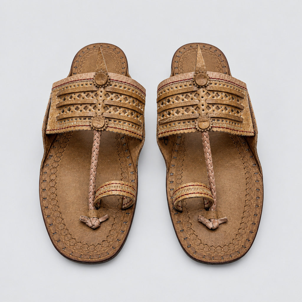 A pair of brown leather thong sandals with intricate woven and cutout details on the straps, laid flat on a light beige marble floor.