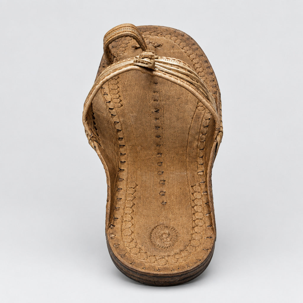 A single brown leather thong sandal with decorative stitching and a small buckle detail, photographed from above on a light beige marble floor with visible cracks.