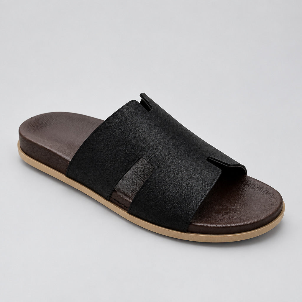 A single men's slide sandal with a wide black textured strap and a dark brown footbed, resting on a polished beige marble floor.