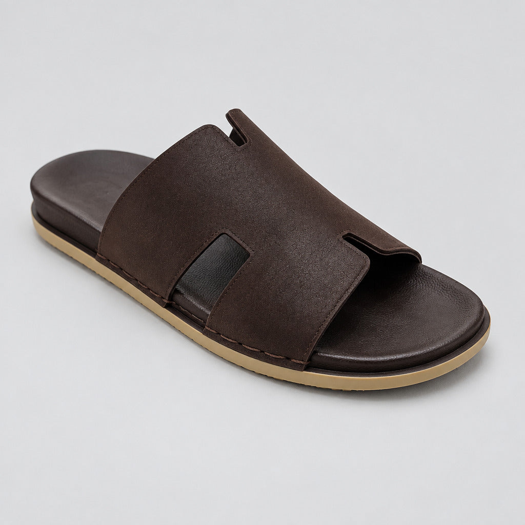 A dark brown leather slide sandal with a thick tan sole, photographed on a polished beige marble floor.