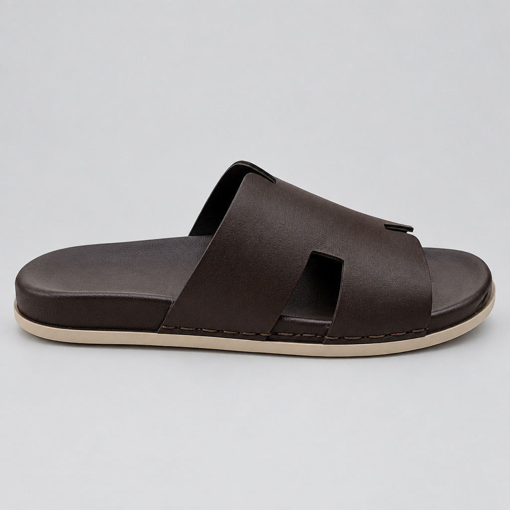 A single dark brown leather slide sandal with a thick black footbed and a beige outsole, resting on a polished marble floor.